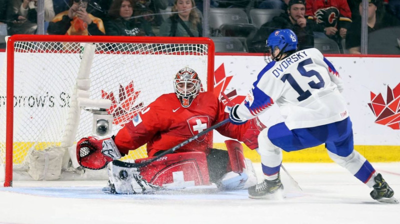 Slovāks Dalibors Dvorskis izgājienā pret Šveices U20 valstsvienības vārtsargu Kevinu Pašu. Foto: IIHF