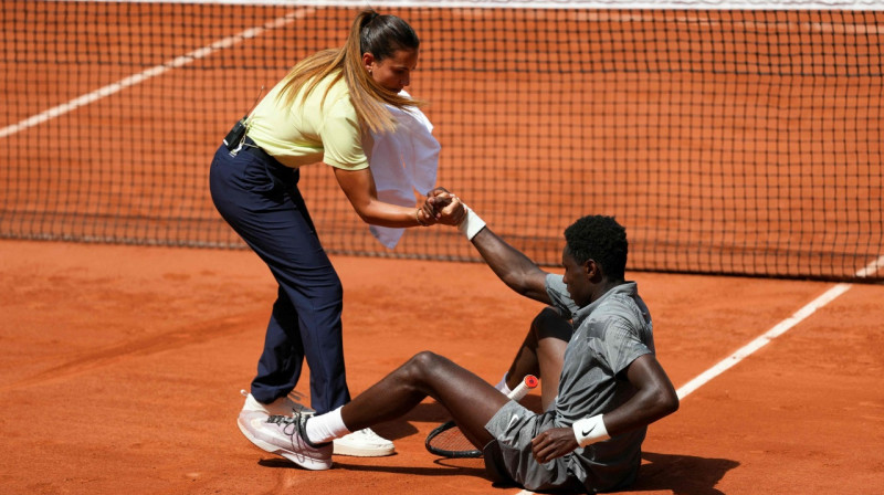 Brazīliešu tiesnese Ana Karvalju palīdz franču tenisistam Moizam Kuamē. Foto: AFP/Scanpix